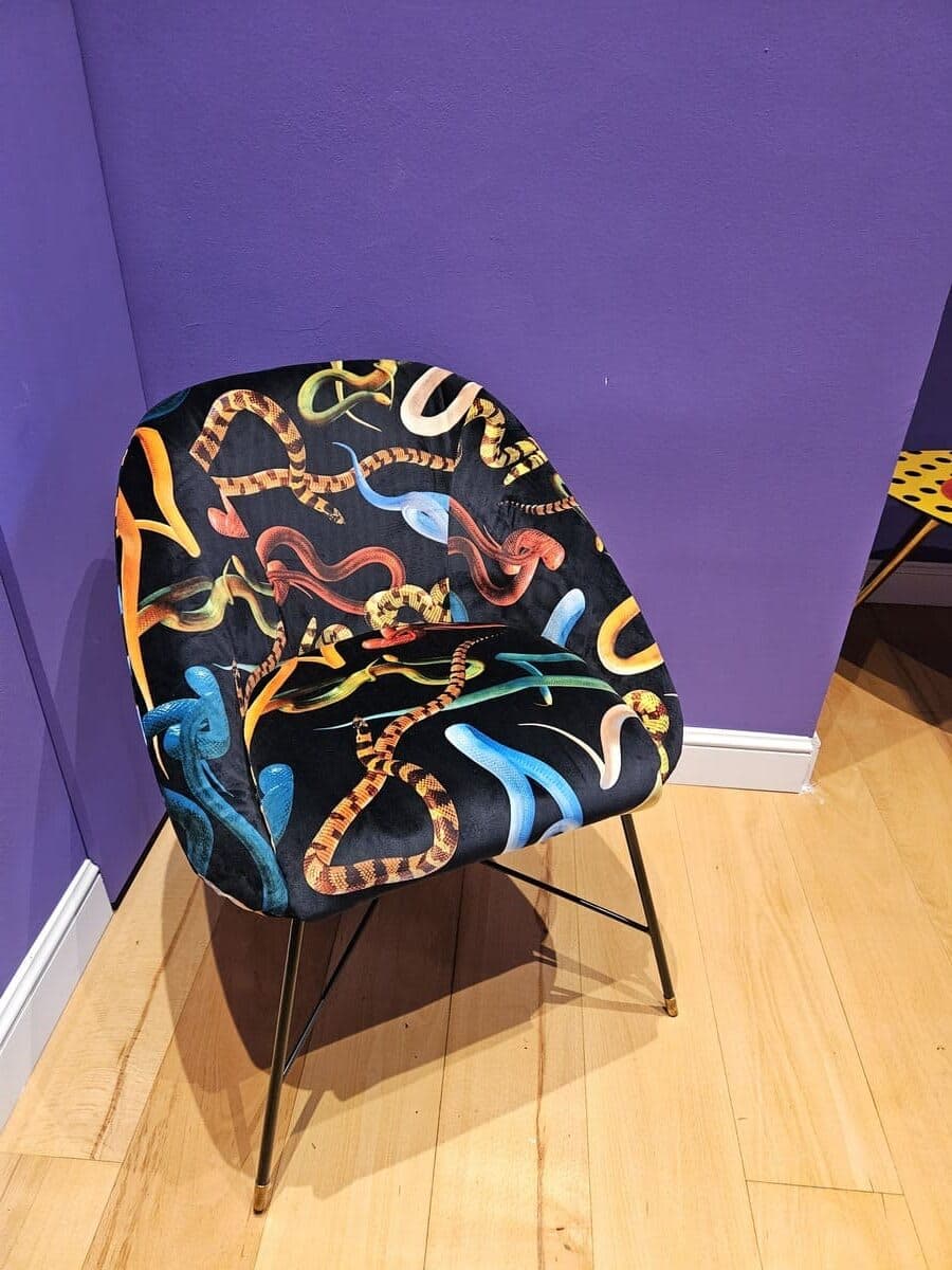 Poltrona Seletti Toiletpaper con stampa serpenti, parete viola e parquet