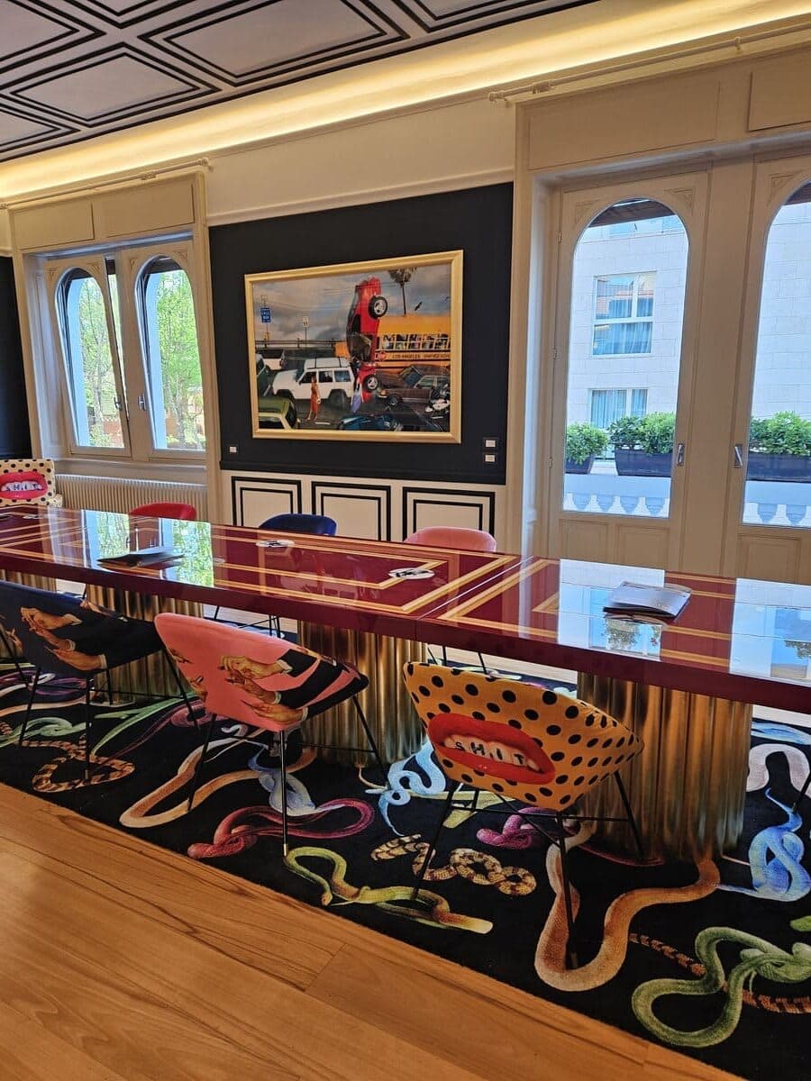 Sala da pranzo con tavolo laccato rosso, sedie Seletti e tappeto Toiletpaper serpenti