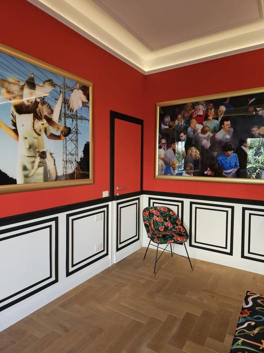 Stanza rossa con grandi fotografie di Alex Prager in cornici dorate e boiserie artigianale