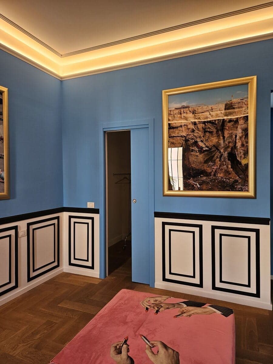 Camera con pareti azzurre, boiserie, fotografia di Alex Prager in cornice dorata e illuminazione LED perimetrale