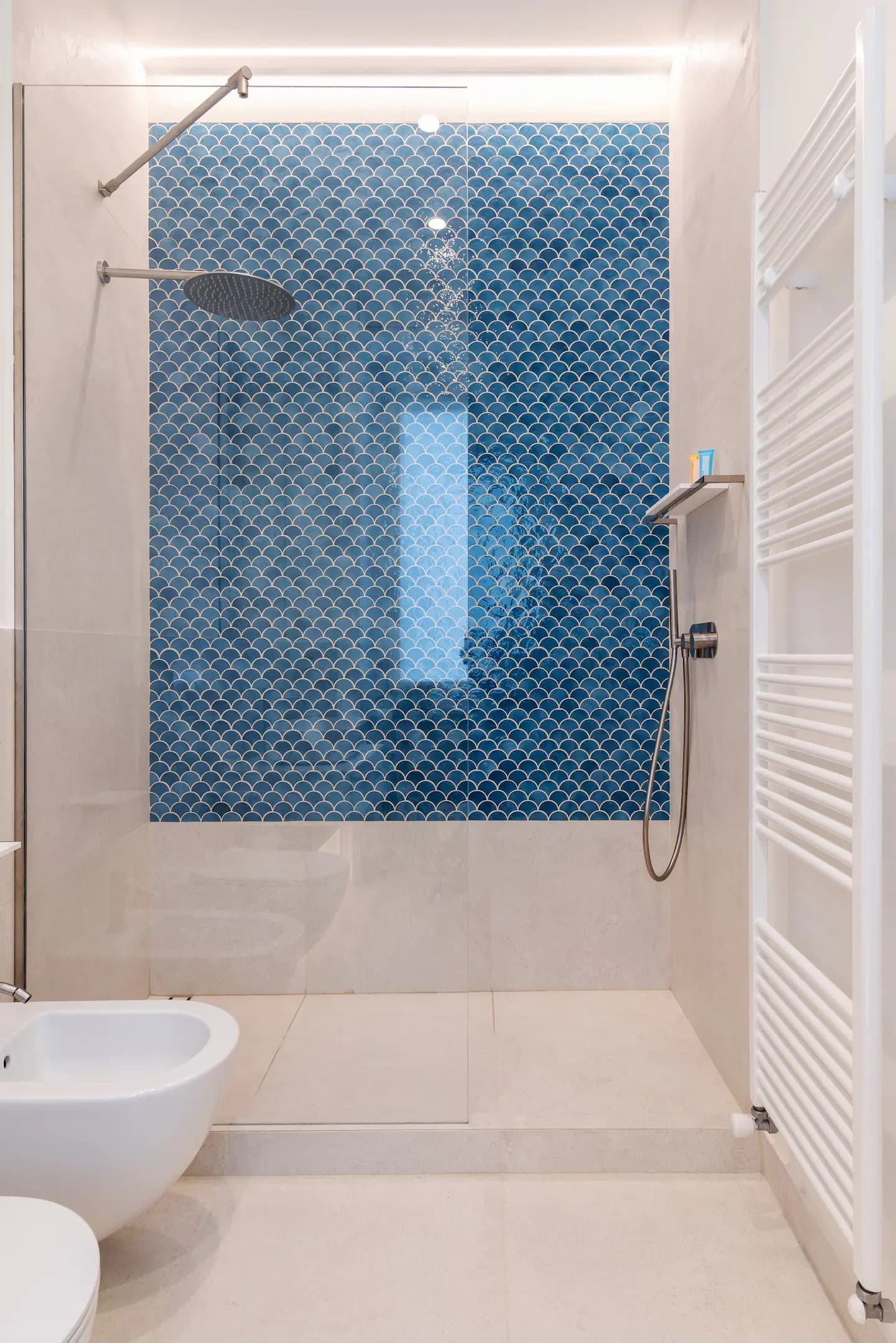 Doccia con parete accent in mosaico a scaglie blu, soffione a pioggia e rivestimento beige