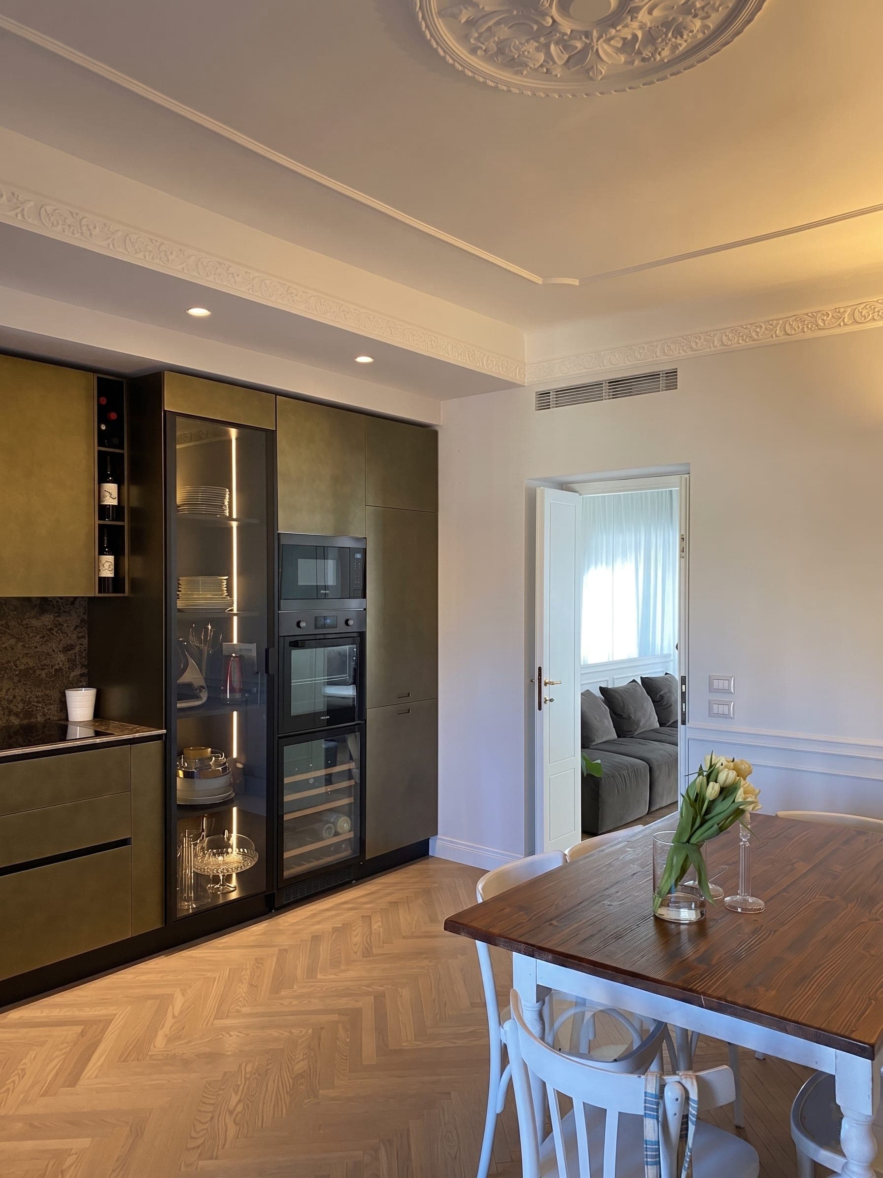 Cucina con ante scure, cantinetta vini, rosone a soffitto e tavolo da pranzo