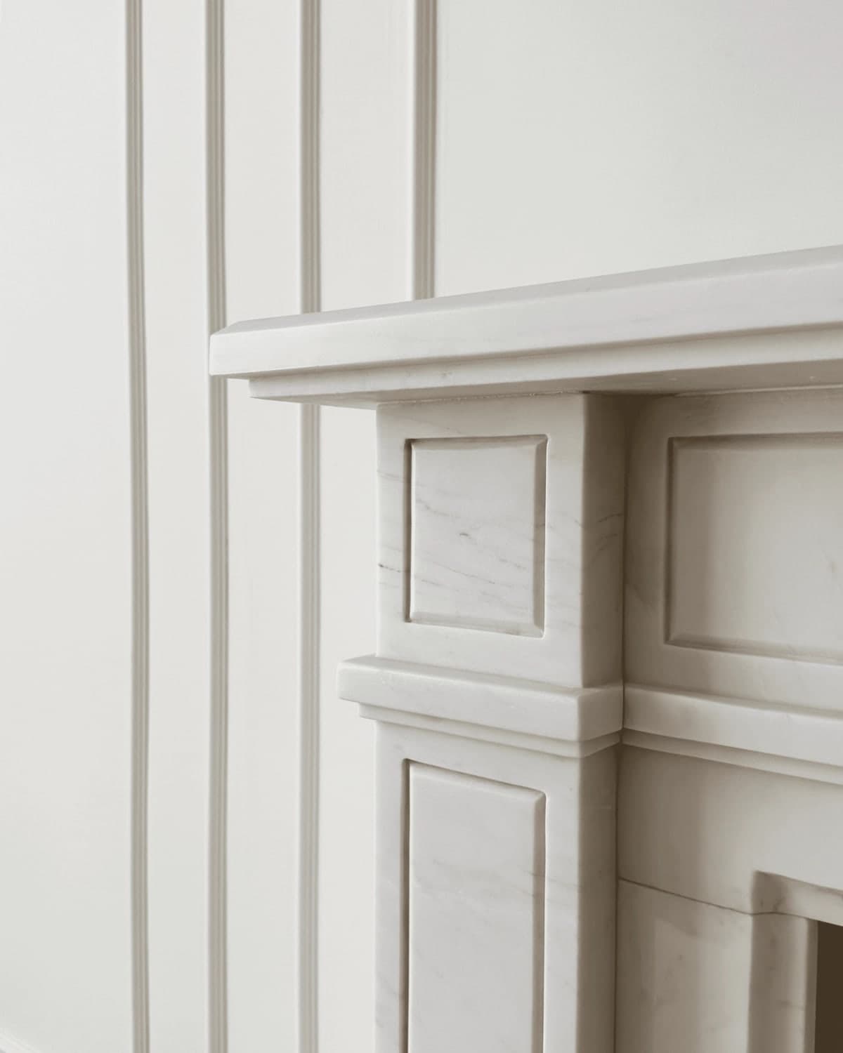 Dettaglio della boiserie bianca e della cornice del camino con modanature