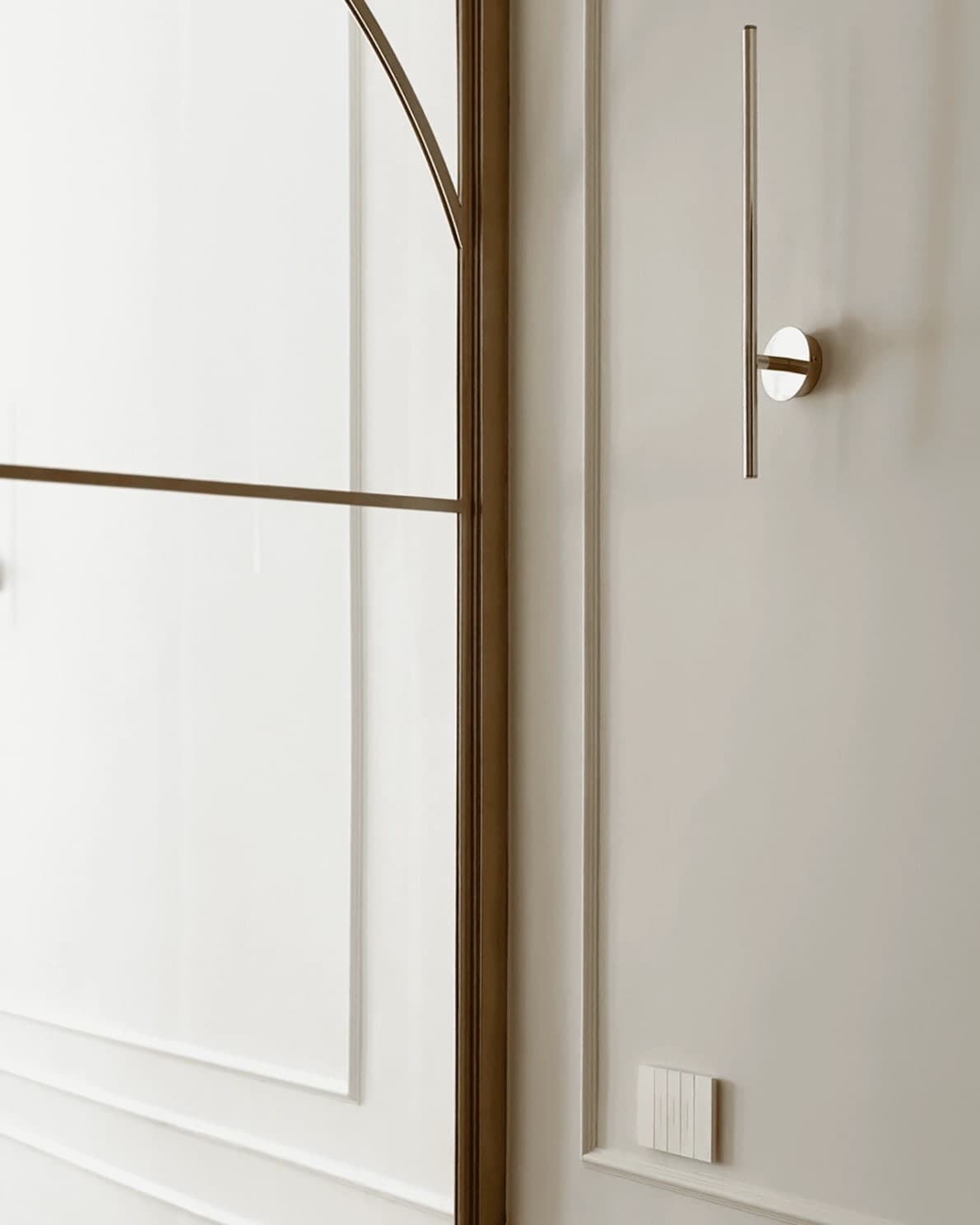 Porta vetrata con profilo in ottone e pannelli di boiserie bianca