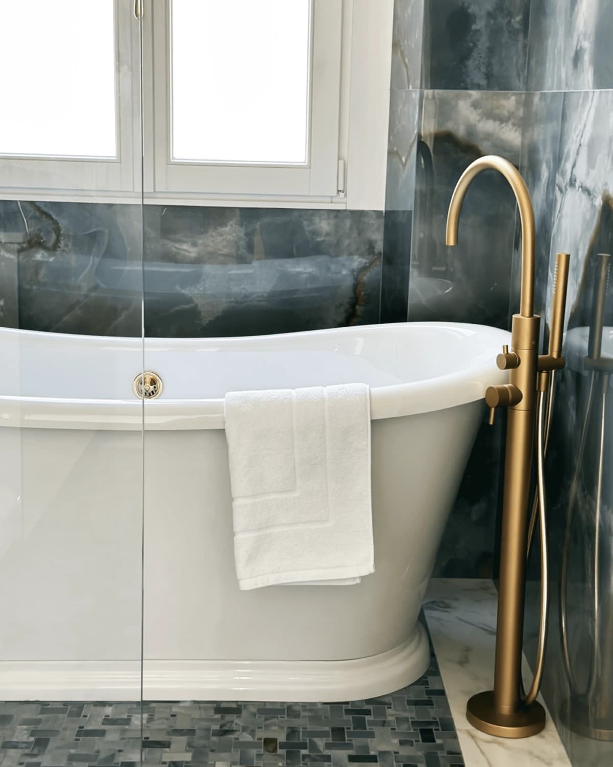 Vasca freestanding con rubinetteria in ottone e parete con rivestimento scuro effetto drammatico