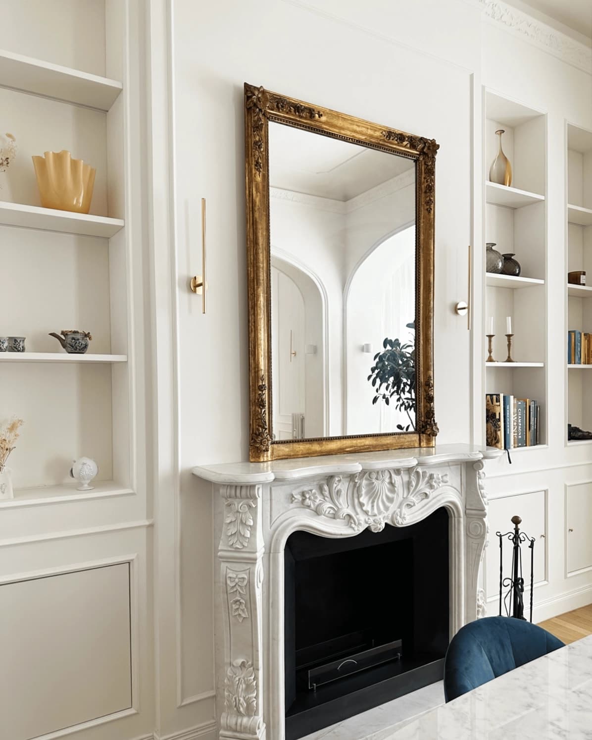 Zona pranzo con sedie in velluto blu, camino decorativo, boiserie e parquet a spina