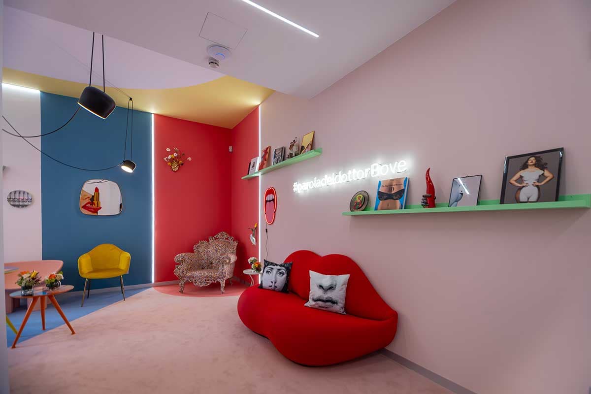 Sala attesa panoramica con divano labbra rosso, poltrona barocca, neon e quadri pop art