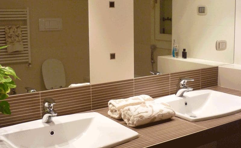 Bagno con doppio lavabo, piano marrone, specchio grande e scaldasalviette