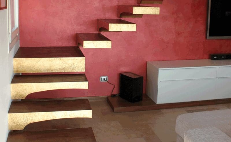Scala a sbalzo con gradini in legno su parete rossa decorativa e mobile TV bianco