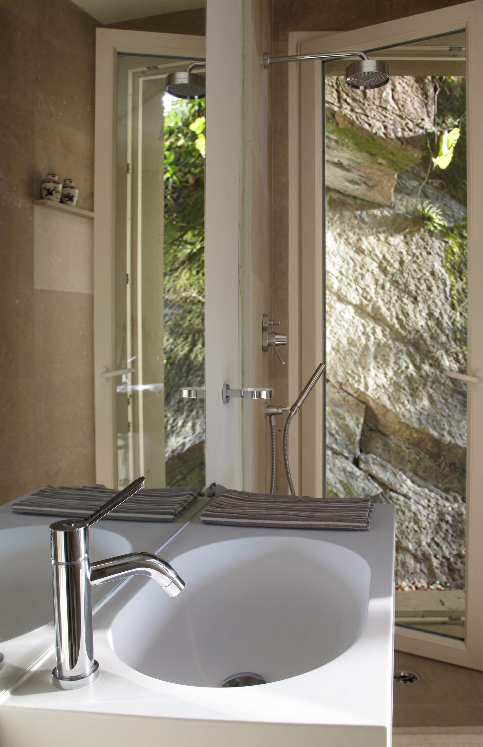 Bagno con lavabo e vista giardino, poltrona vintage con quadro rosso e scaffale