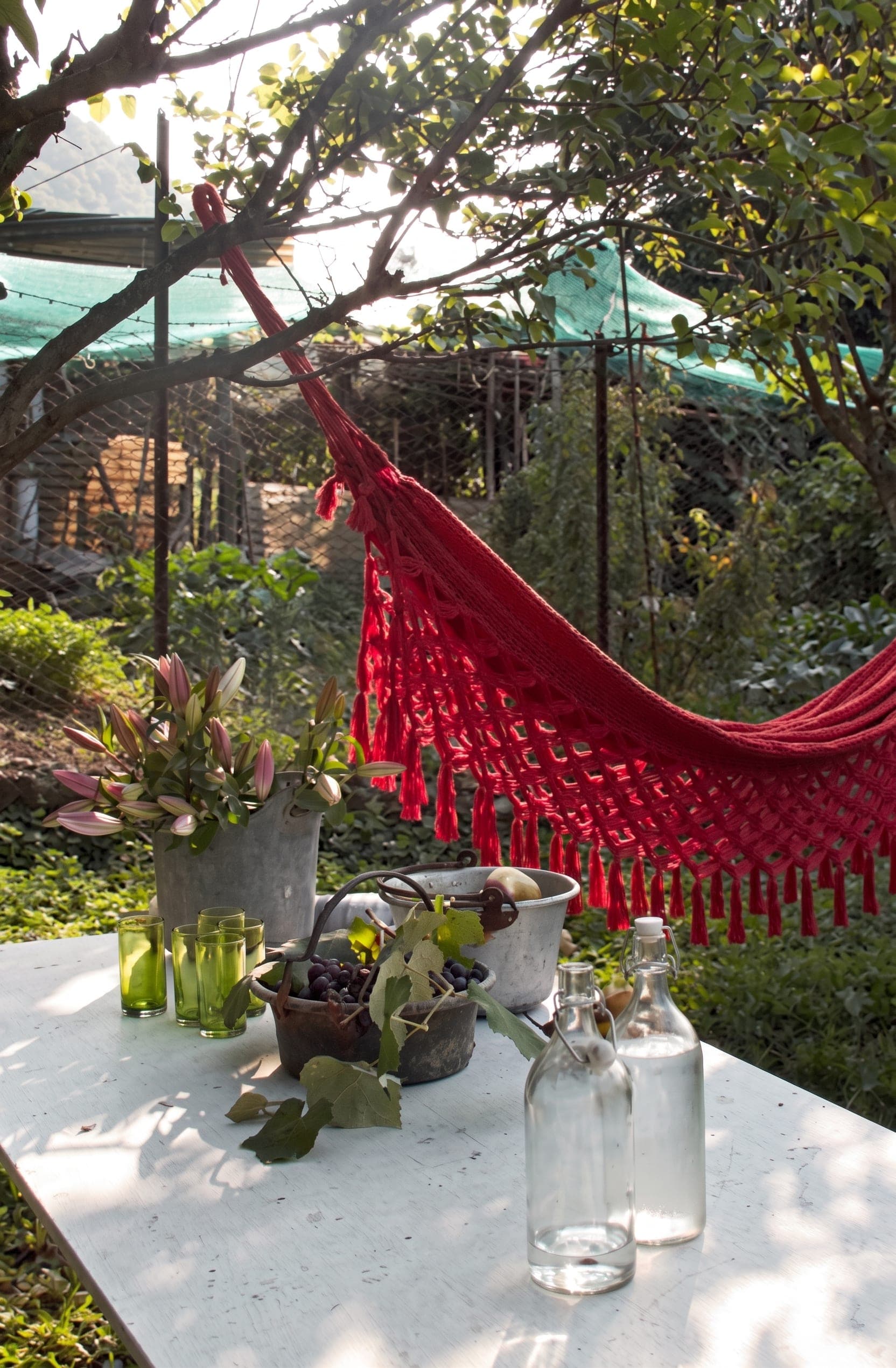 Cucina con piatti decorativi a parete e giardino esterno con amaca rossa e tavolo