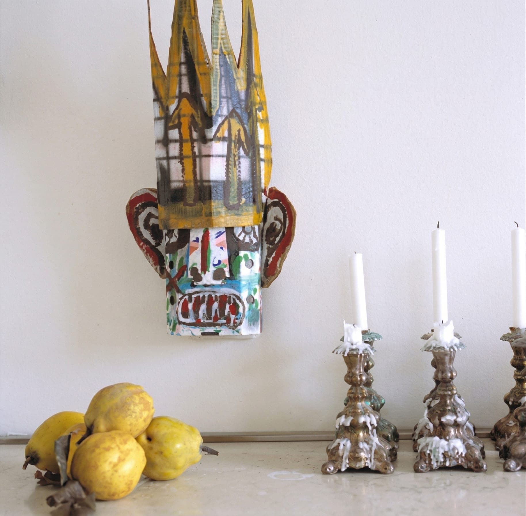 Dettaglio maschera decorativa orientale, candelabri argentati e limoni su console