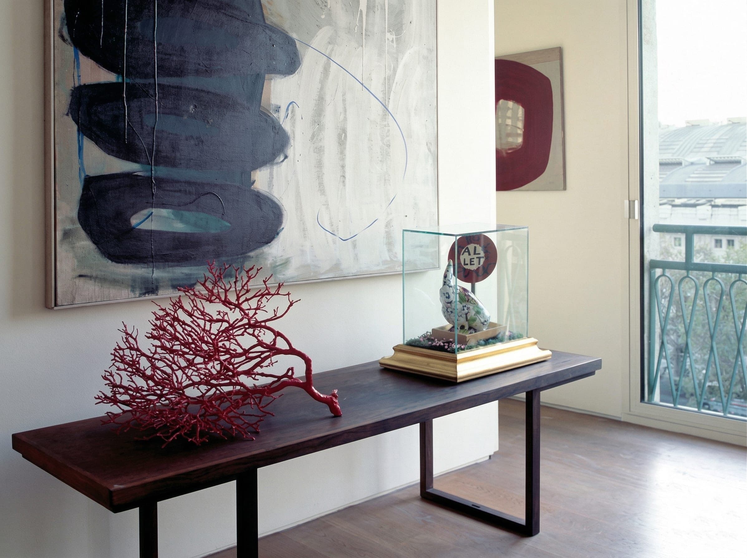 Console con quadro astratto blu, ramo di corallo rosso e scultura sotto teca in vetro